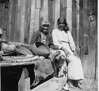 Chuckachancy women pause in their work preparing acorns for grinding, California, c. 1920