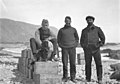 Trois hommes et un chien posant pour une photographie.