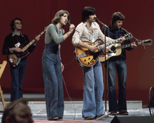 Colour photograph of Peter, Sue and Mark performing in a rehearsal on the 1976 contest stage.