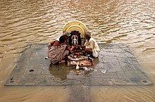 A puja performed on the banks of the overflowing Shipra River in Ujjain during the summer monsoon. Flood puja.jpg