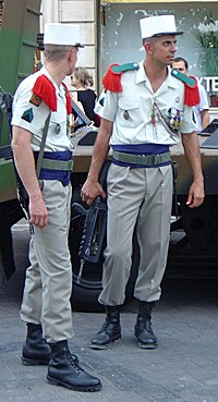 Légionnaires in modern dress uniform. Note the green and red epaulettes and the distinctive white kepi. They carry France's standard assault rifle, the FAMAS.