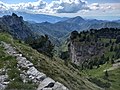 Monte Caplone, la valle di Campei e sullo sfondo il monte Denervo e il lago di Garda. A sinistra le guglie del torrione scalate da Hans Reinl