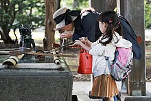 A mother and daughter purify themselves before entering a Shinto shrine Purifying before entering a shrine; October 2019.jpg