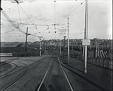 A junction between two streetcar lines, with a rail yard in the background