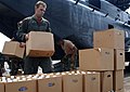 Humanitarian aid (bottled water) being handled by military personnel: Half slotted containers with hand-holes