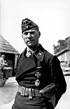 A man wearing a military uniform with an Iron Cross displayed at the front of his uniform collar.