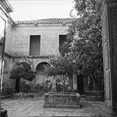 Photographie en noir et blanc d'un cloître ancien dallé.