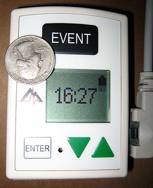 English: A Holter monitor with a US quarter do...