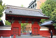 Foto a colori della porta di entrata rossa e del muro di cinta rosso e bianco dell'Università di Tokyo.