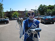 A man dressed as Xenu carrying an E-meter; Scientology's critics often use Xenu to mock the movement. XenuWithE-Meter.jpg