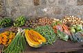 All these vegetables (and the star fruit and coconuts) were grown locally in Gingerland on the island of Nevis (St Kitts & Nevis). Counterclockwise from the lower left there is: star fruit (with taro root behind them), scallions, a cut piece of tropical pumpkin with cucumbers behind it, green beans (behind the green beans are white sweet potatoes), carrots, okra in bags, the herb thyme in bags, savory peppers (red and green in a bag), spiny and smooth christophene behind the thyme and peppers, in the back row from right to left are onions, coconuts, potatoes, butternut squash with small ?breadfruit in front of it, potatoes, beets?, green bananas, and green plantains.