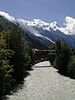 Řeka Arve ve městě Chamonix-Mont-Blanc. Po mostě projíždí vlak třídy Z 800 společnosti SNCF na trati Saint-Gervais-Vallorcine. V pozadí je vidět horu Mont Blanc, Montblanský masiv a zejména Bossonský ledovec