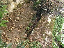 Photographie en couleurs d'un sarcophage creusé dans la roche du sol d'une chapelle.