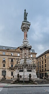 El Monumento a los Fueros. Detrás se observa el edificio del Banco de España.