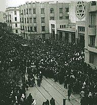 Vänster: Den huvudsakliga miljön för Rabbinens katt är mellankrigstidens Alger (foto från 1921), även om stadens namn aldrig nämns. Höger: Fram till andra världskriget och staten Israels tillkomst fanns en levande judisk kultur i stora delar av Nordafrika. På fotot (Tunis, 1941) samlas folkmassor utanför Stora synagogan i samband med Rabbin Boccaras begravning.