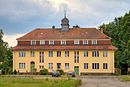 Gutsanlage mit Herrenhaus einschließlich Zufahrtsbereich mit Torpfeilern sowie Gutspark mit Pergola und drei Parkplastiken einschließlich Wirtschaftshof in Anlage und Grundriss mit Verwalterhaus, Wasch- und Heizhaus, Pferdestall, Bretterscheune sowie Lage und Grundform (Kubatur) der die westliche Gutshofsseite begrenzenden historischen Wohn- und Wirtschaftsgebäude