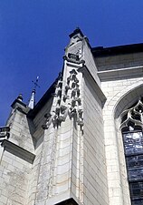 Vue d'un contrefort d'église surmonté d'une décoration de pinacles surmontés d'un blason.