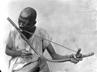 Представитель народа обу (Нигерия) играет на музыкальном луке