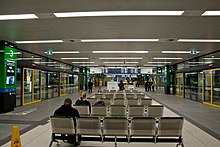 Underground waiting area surrounded by glass windows into the busway