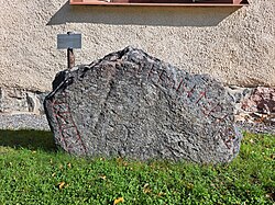 Stenen är placerad intill kyrkväggen
