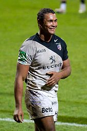 Joueur de rugby, vue de trois quart, souriant.