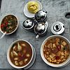 A Tibetan meal with (clockwise from top) tingmo (steamed bread), thenthuk (noodle soup), momos in soup, vegetable gravy, and condiments in center from the Himalaya Restaurant