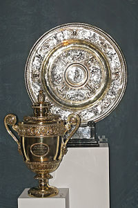 A golden trophy, in the shape of a loving-cup, next to a silver plate