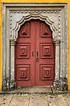 Large brown wooden entrance door with stone arch at Palácio Nacional da Pena