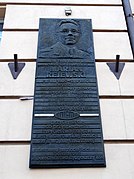 Photographie d'une plaque commémorative accrochée à un mur avec le visage de Rejewski et un texte.