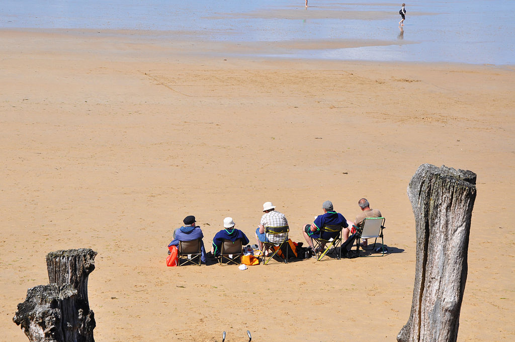Elderly people sit on the beach.