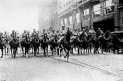 Photos noir et blanc de cavaliers avançant en ville par douze de front, commandant en tête.