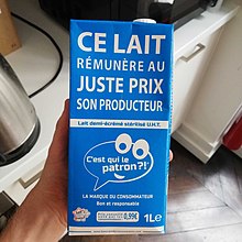 Brique de lait bleue C'est qui le Patron ?! tenue dans une main