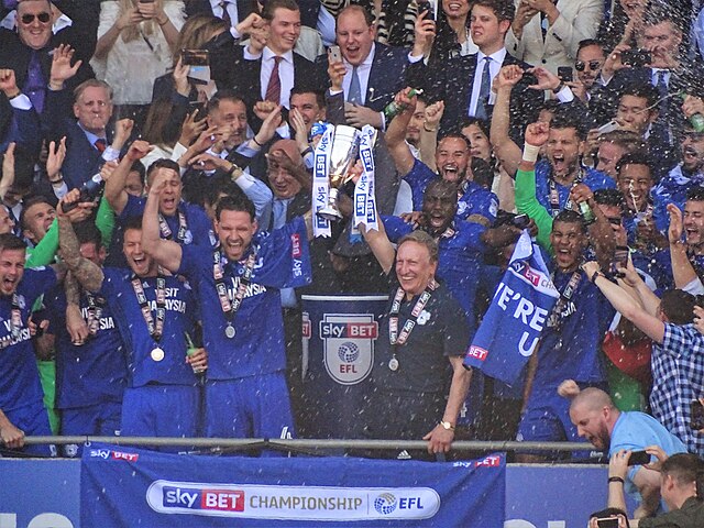 A football team celebrating and lifting a trophy