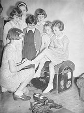 1940: A group of girls evacuated from the Channel Islands to Marple, on mainland Britain, try on clothes and shoes donated by the United States. Channel Island Evacuees Try on American Clothing in Marple, Cheshire, England, 1940 D742.jpg