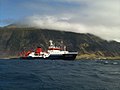 A German ship in Tristan da Cunha. In the back is Queen Mary's Peak and to the right is Edinburgh of the Seven Seas.