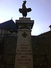 Photographie d'une colonne carrée surmontée de la statue d'un coq