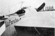 Photo noir et blanc d'un avion monoplan, prise en biais de derrière le cockpit