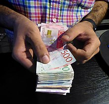 A person counts a bundle of different Swedish banknotes. Pengar - 2019.jpg