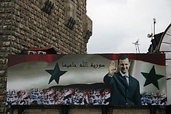 Billboard with a portrait of Bashar al-Assad and the text 'Syria is protected by God' on the old city wall of Damascus in 2006 Syria.BasharAlAssad.02.jpg