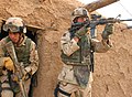 Le Staff Sergeant Fritz Autenrieth, de la 3rd Infantry Division, couvre son supérieur pendant une fouille d'une maison en Irak.