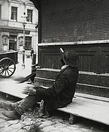 A man drinking from a bottle of liquor while sitting on a boardwalk, c. 1905-1914. Picture by Austrian photographer Emil Mayer. Emil Mayer 024.jpg