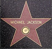 A pink star with a gold colored rim and the writing "Michael Jackson" in its center. The star is indented into the ground and is surrounded by a marble colored floor.