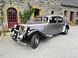 Une Citroën Traction 11 BL (Berline Légère) des années 1950, dans une belle et rutilante livrée grise métallisée avec les ailes noires.