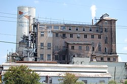 A row of large corrugated metal buildings with a large smokestack reading "CINCLARE".