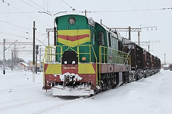 Československá dieselová lokomotiva řady ČME3 s pluhem a nákladními vozy ve stanici ukrajinské Vinnycji