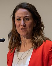Foto einer Frau mit braunen Haaren, die eine Rede hält