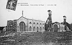 Photo noir et blanc un ensemble de bâtiments industriels typés 1900 avec deux grands chevalements (tour avec bigue) métalliques et cheminée d'usine.