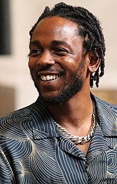 A portrait of Lamar, an African-American man. He is wearing a cornrow hairstyle, an embroidered shirt and a gold necklace