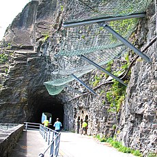 Image of rock tunnel (background) and rockfall protection mesh a rock cliff face (foreground)