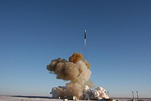 Carrier rocket flies up in the blue sky, above a large cloud of brownish smoke